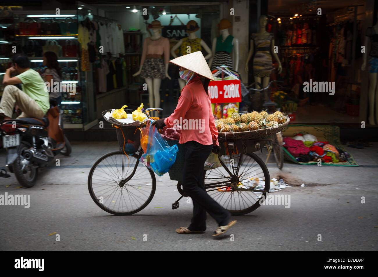 Una signora vendita di ananassi dalla sua bicicletta nel quartiere vecchio di Hanoi Foto Stock