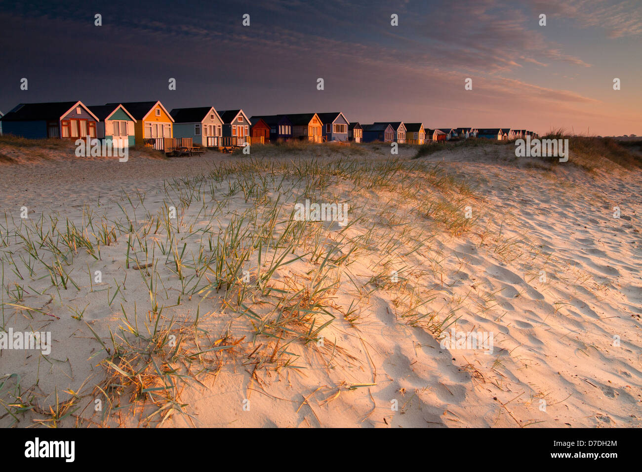La prima luce del giorno che colpisce le capanne di spiaggia e dune a testa Hengistbury. Foto Stock