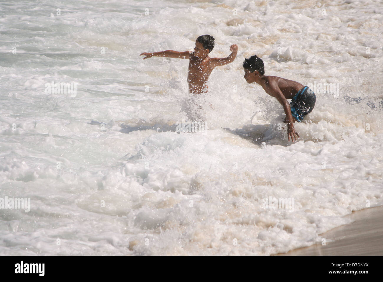 Due ragazzi di divertirsi con le onde di rotolamento a Leme Beach, su una soleggiata giornata autunnale. Rio de Janeiro, Brasile Foto Stock