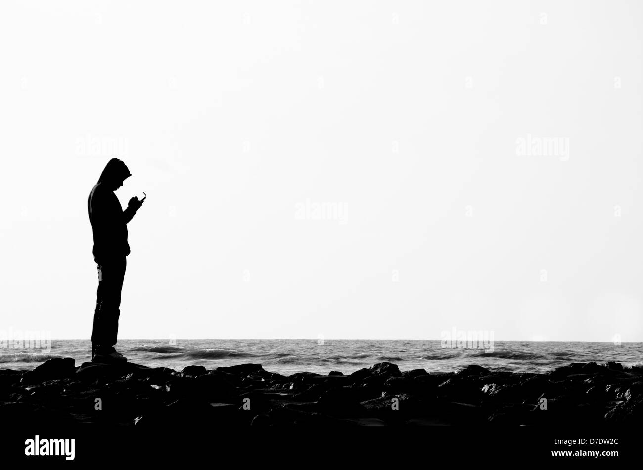 Silhouette di uomo utilizza lo smartphone sulla spiaggia con una stanza per il testo. Foto Stock
