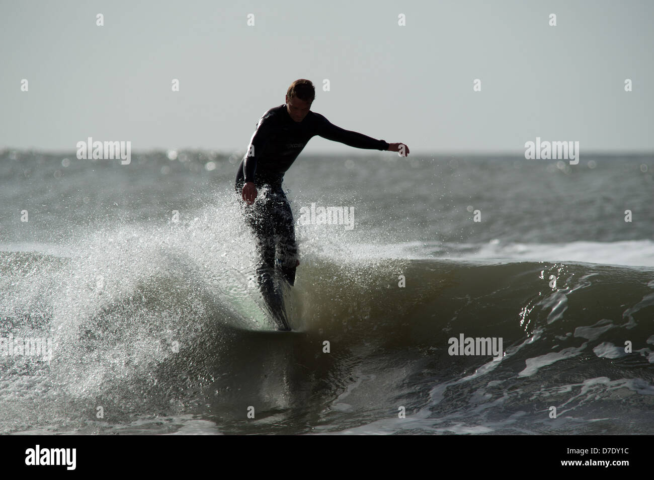 Un pennacchio di spray solleva la punta della tavola in un classico appendere cinque in un Gower sessione di navigazione in Galles, Regno Unito Foto Stock