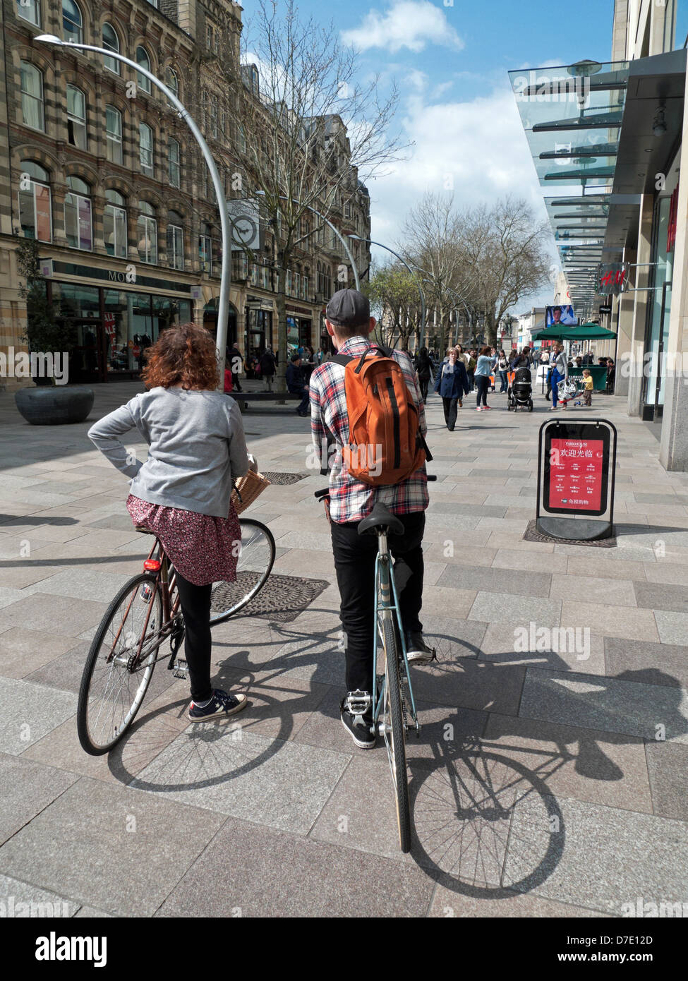 Una coppia sulle bici che guardano lungo lo shopping pedonale street nel centro di Cardiff, zona St Davids 2 in Primavera Galles Regno Unito KATHY DEWITT Foto Stock