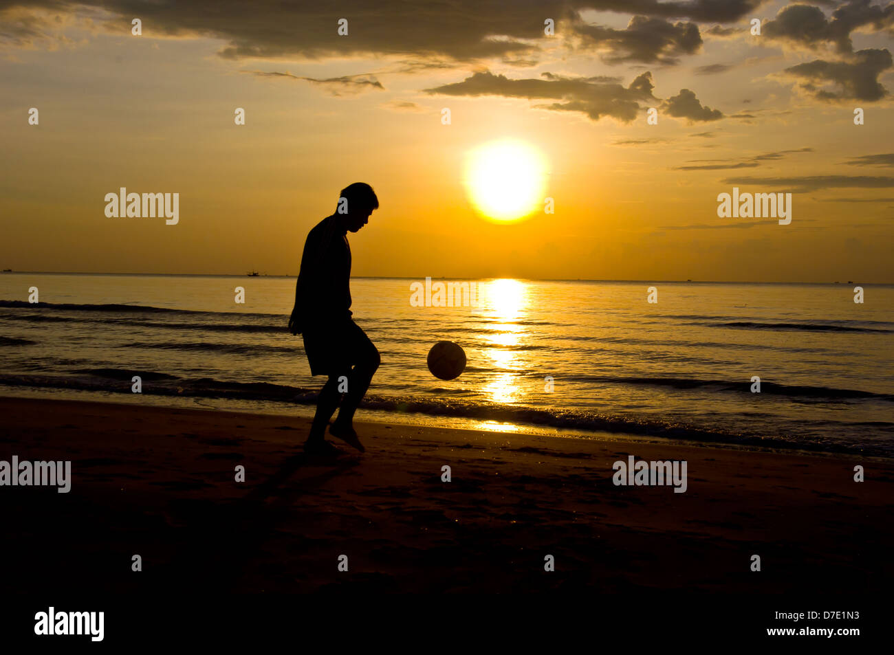 Silhouette di uomo giocare a calcio sulla spiaggia Foto Stock