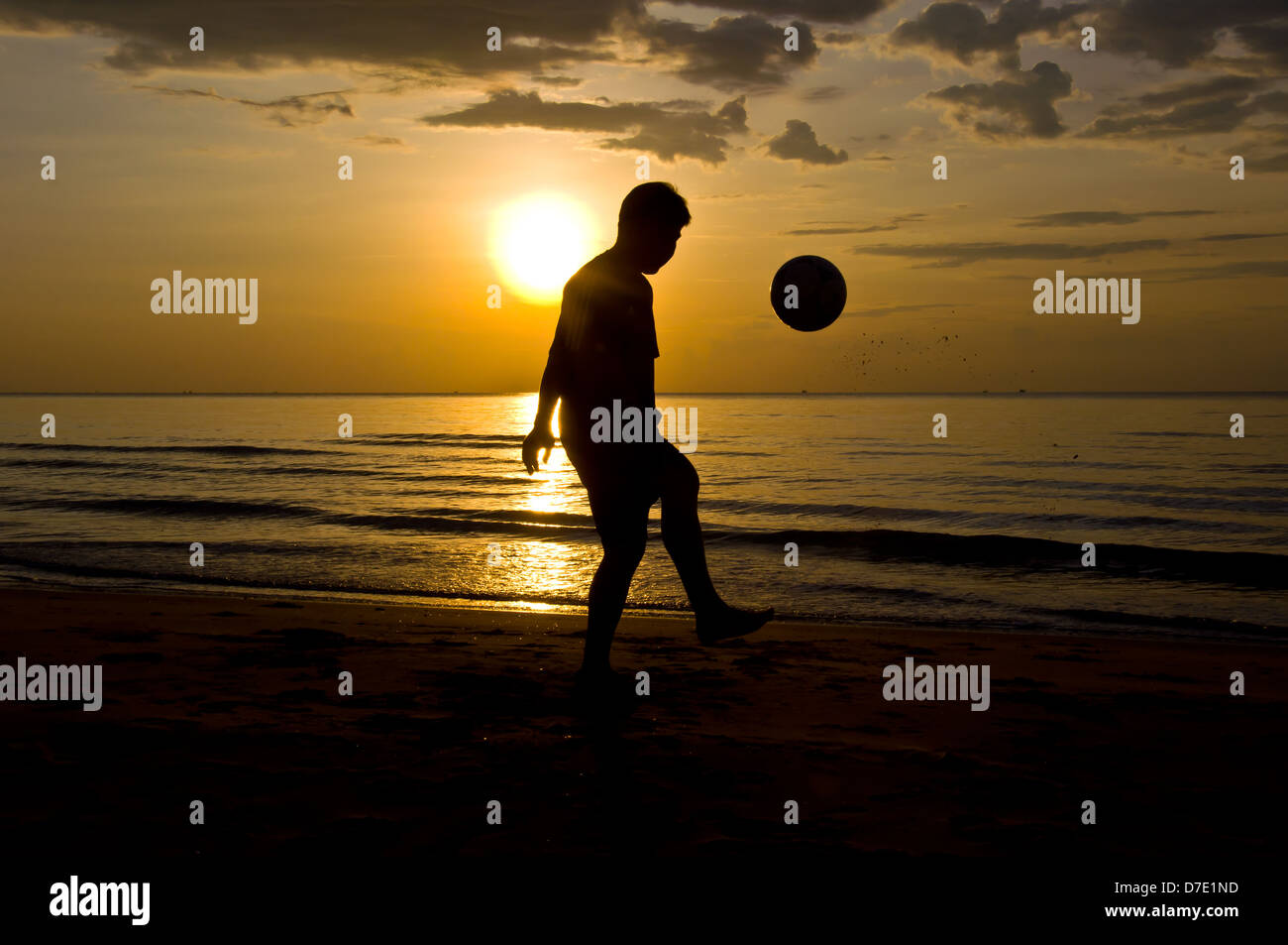 Silhouette di uomo giocare a calcio sulla spiaggia Foto Stock