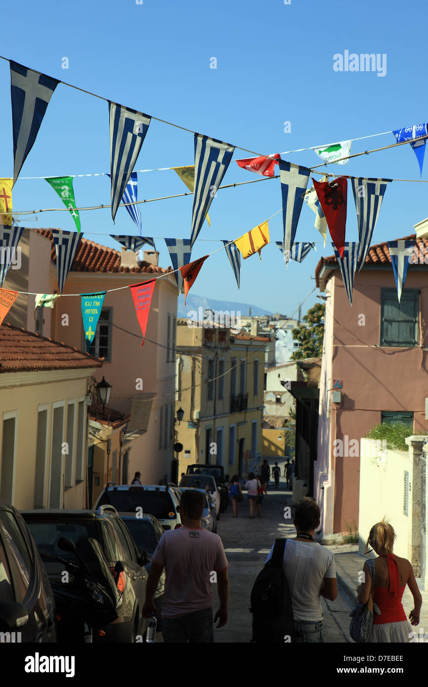 Persone passeggiando per le stradine del quartiere Plaka di Atene con le bandiere Greca infilate tra gli edifici Foto Stock