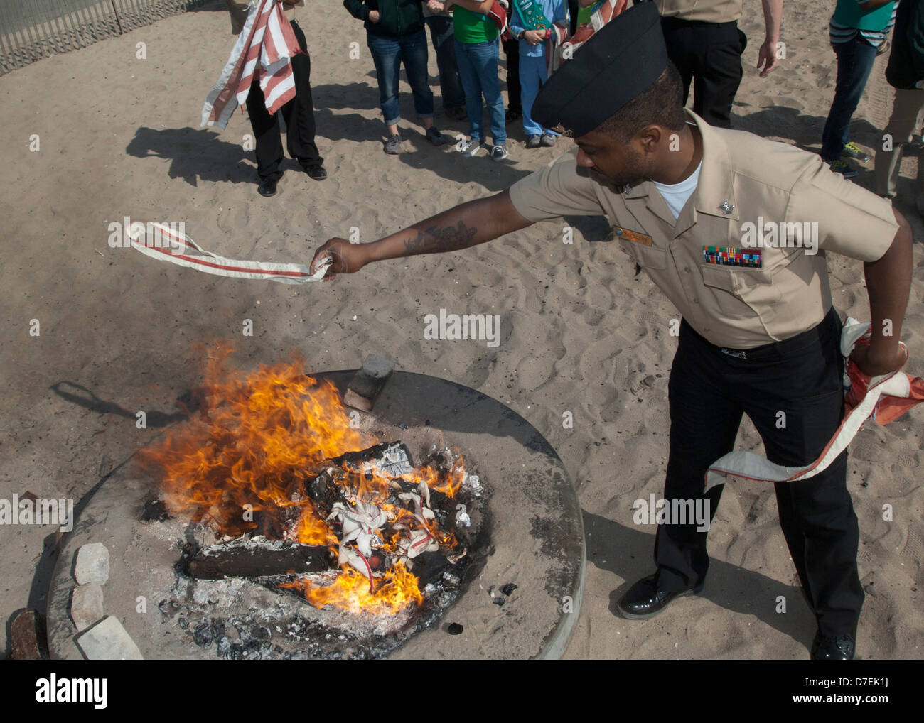 Un marinaio aiuta a ritirarsi un flag. Foto Stock