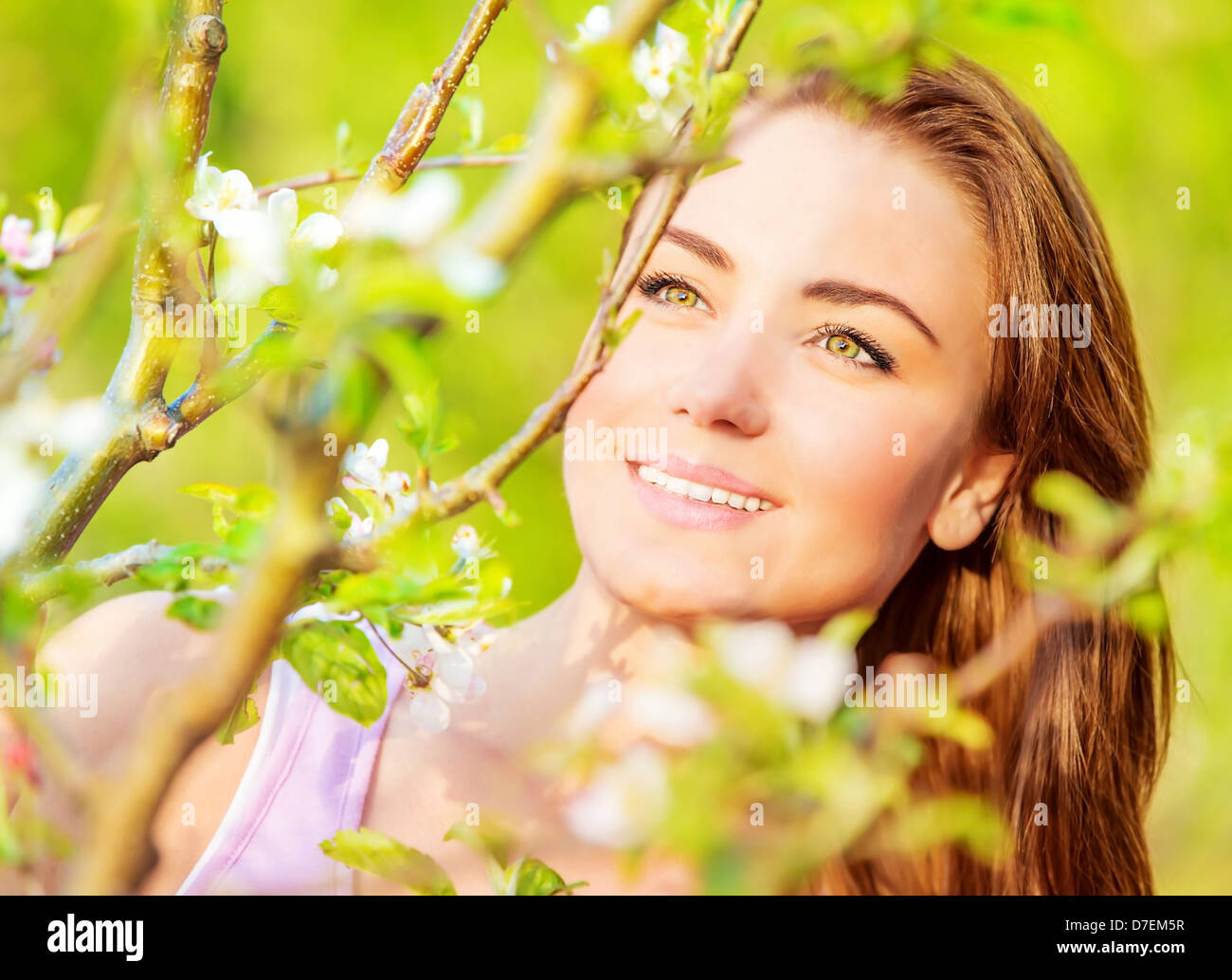 Closeup Ritratto di giovane attraente signora avendo divertimento all'aperto, la molla natura, albero apple blossom, giornata soleggiata, concetto di felicità Foto Stock