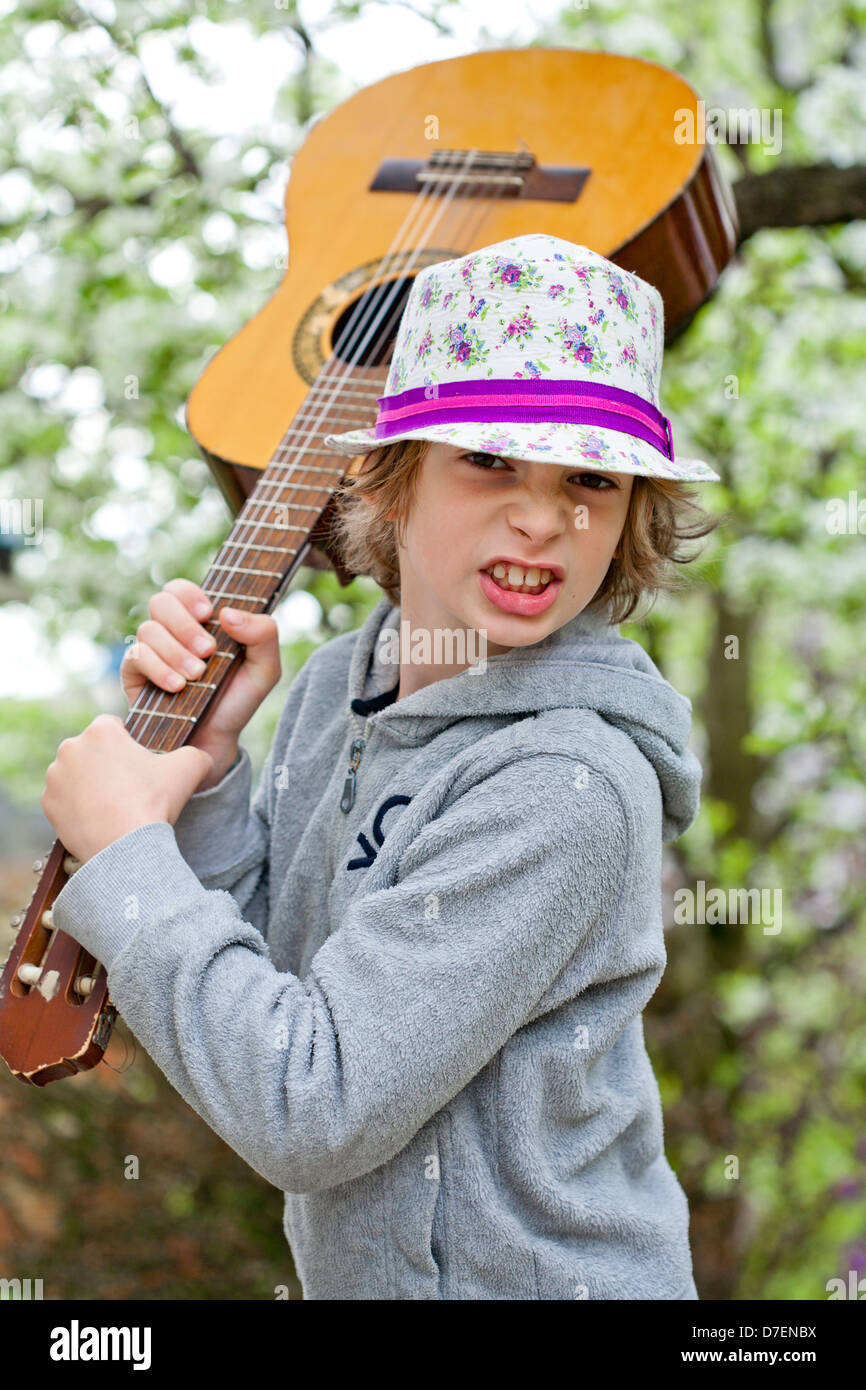 Ritratto di un ragazzo suonando una chitarra acustica all'aperto nel giardino. Foto Stock