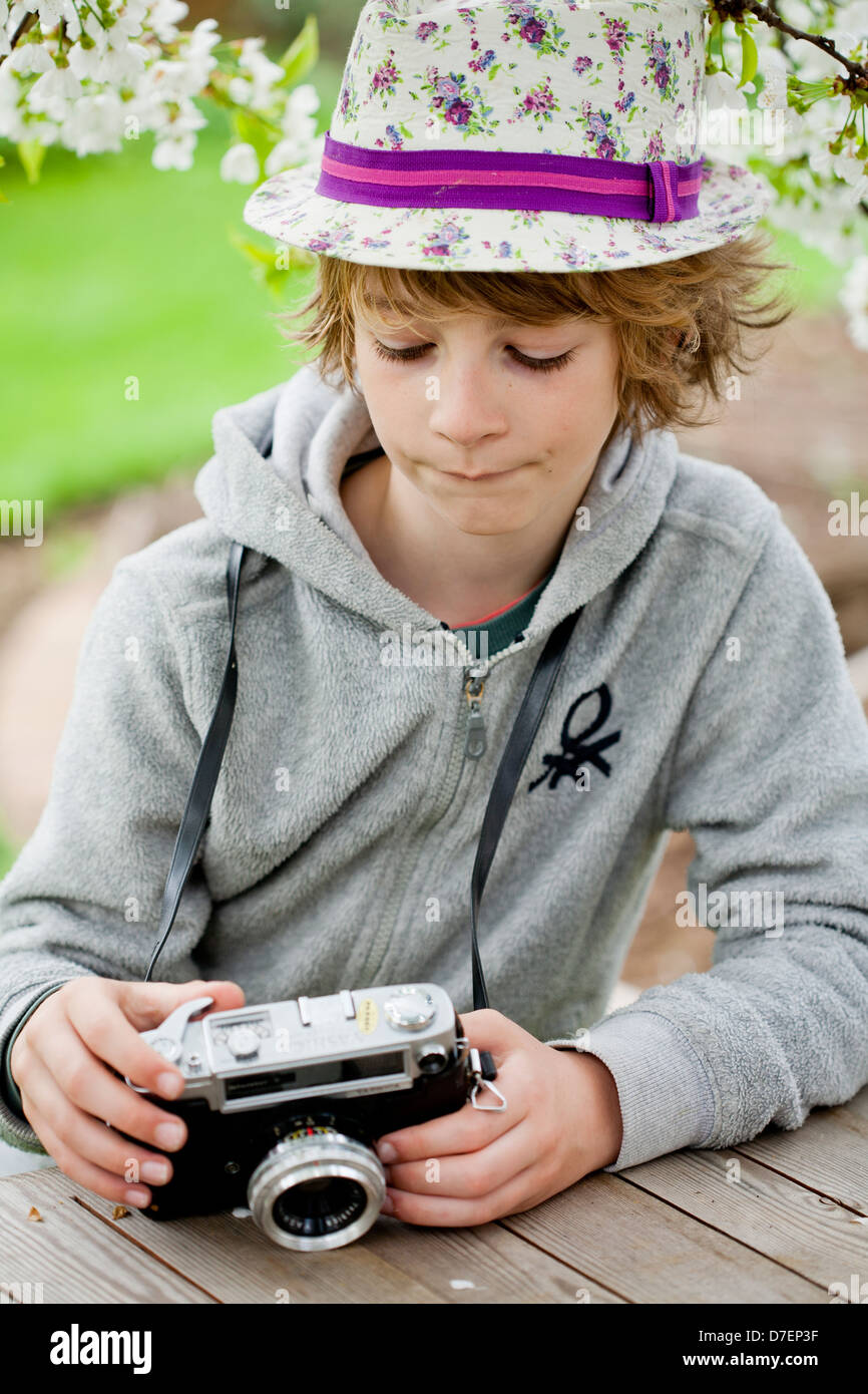 Ritratto di un ragazzo giocando all'aperto con una vecchia macchina fotografica. Foto Stock