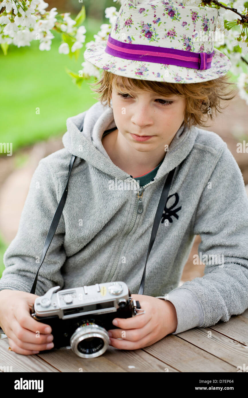 Ritratto di un ragazzo giocando all'aperto con una vecchia macchina fotografica. Foto Stock