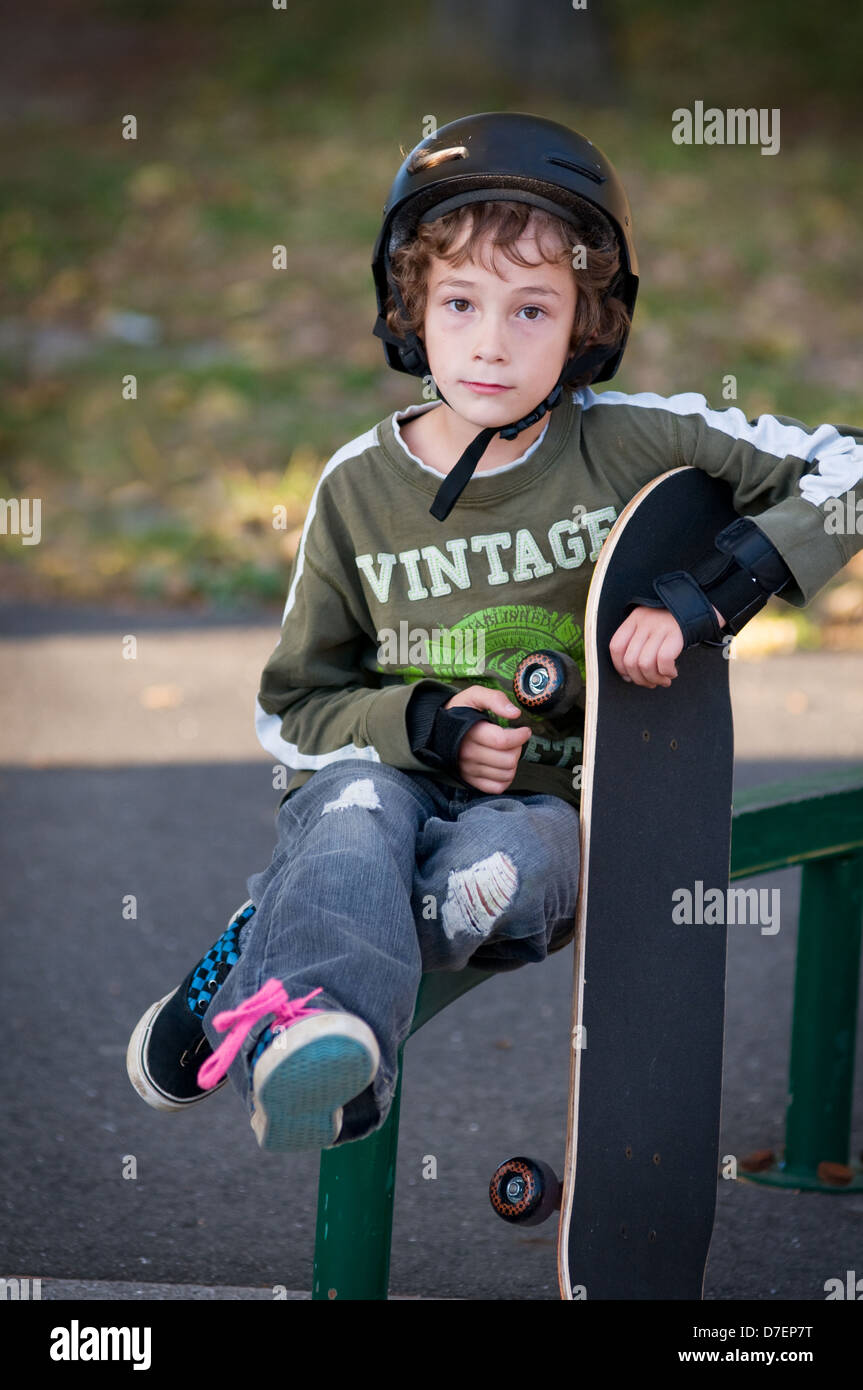 Giovane ragazzo indossare attrezzature di sicurezza learning per skateboard in un locale amor outdoor parco su una bella serata di caduta Foto Stock