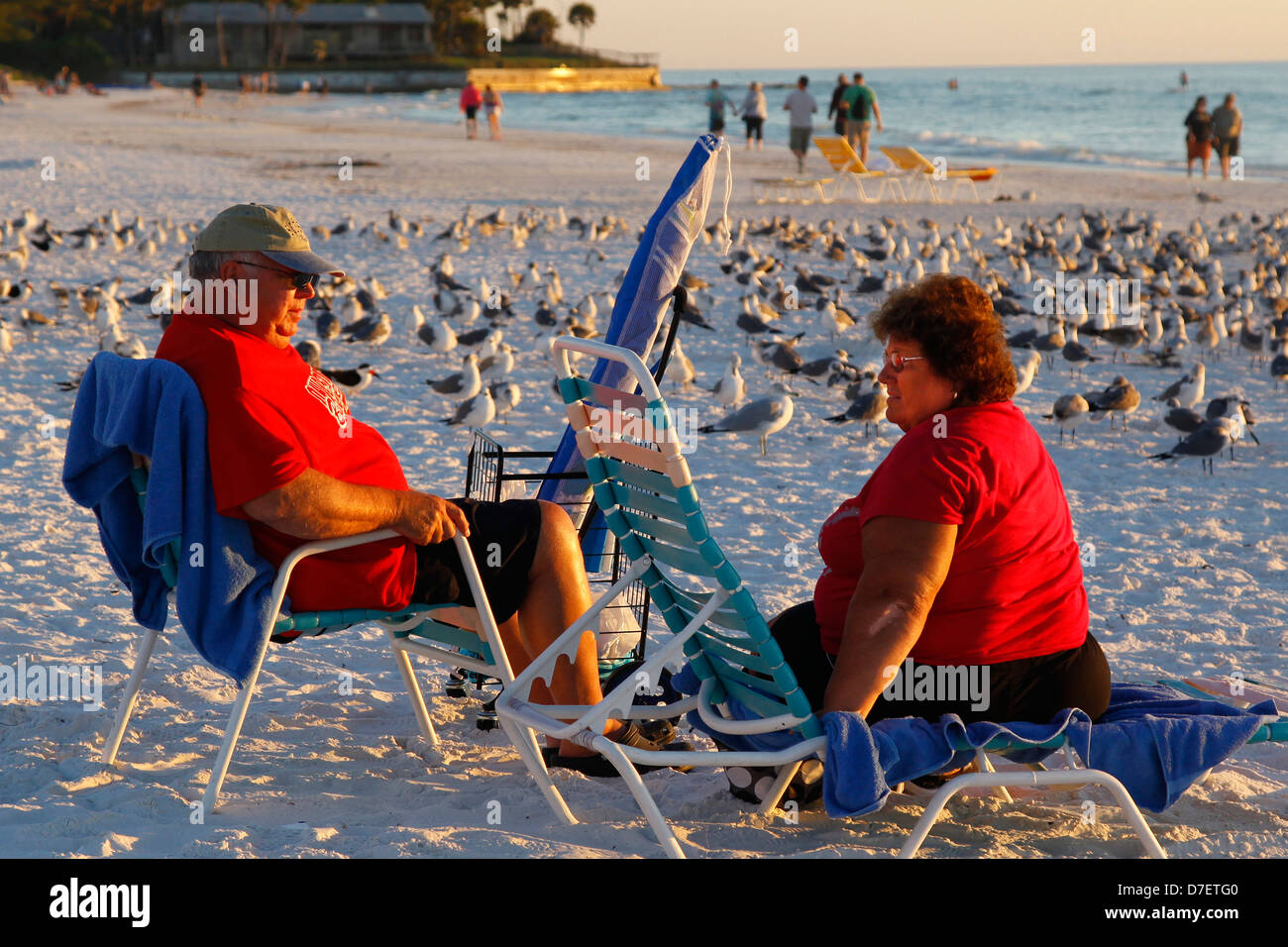 Il sovrappeso coppia senior godervi la spiaggia al tramonto con i gabbiani Foto Stock