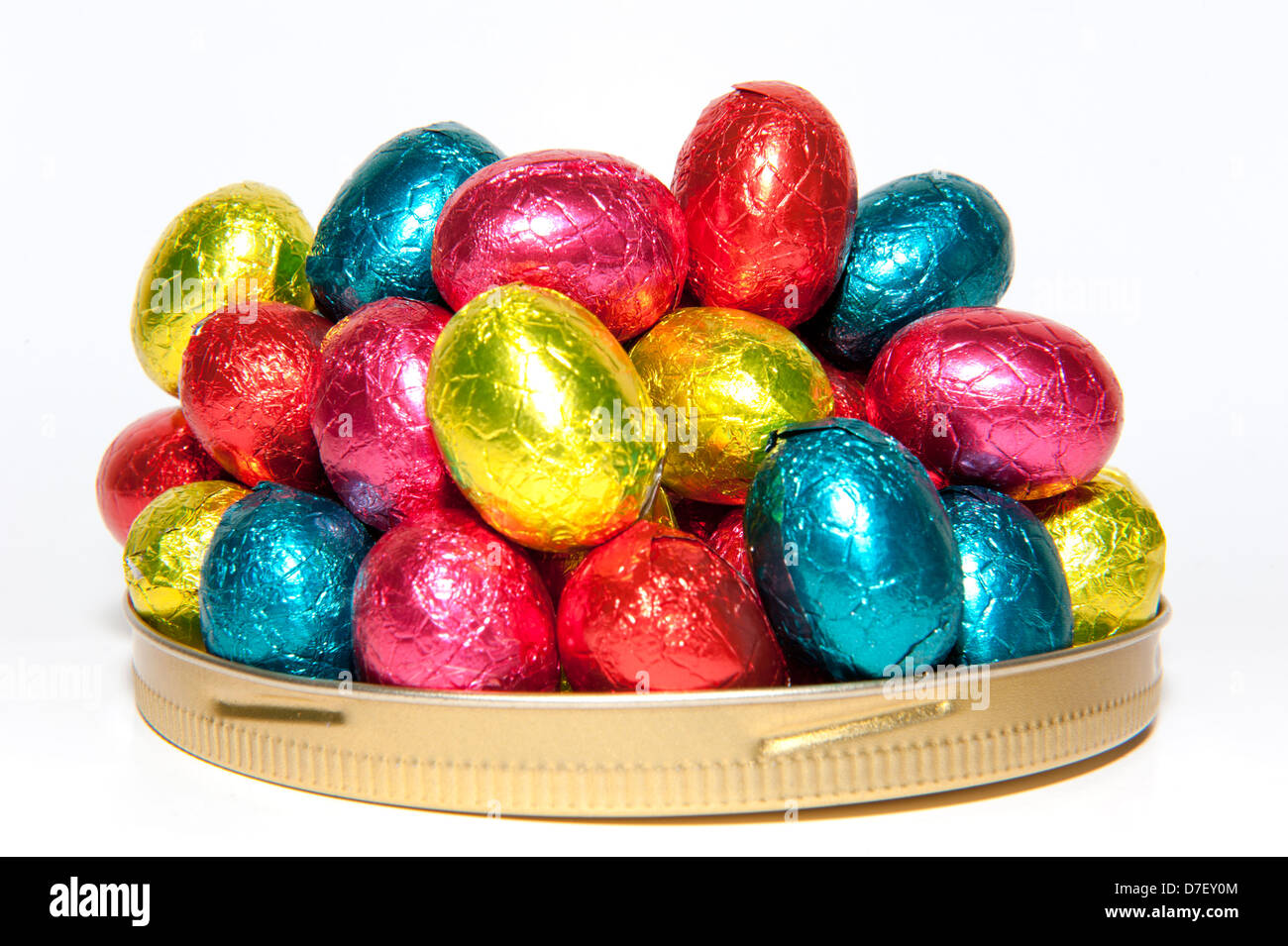 Cioccolato colorato Pasqua uova imballate in una pila su un piatto, isolato su sfondo bianco Foto Stock