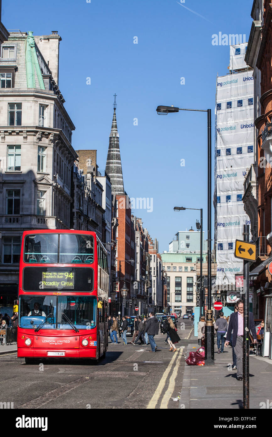 Un double-decker bus che si muove lungo una strada nel centro di Londra, Inghilterra, Regno Unito Foto Stock