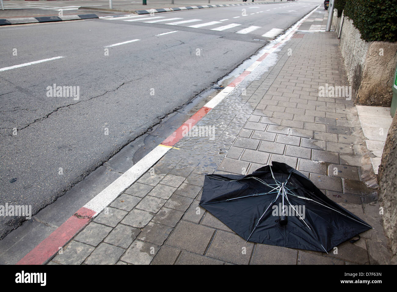 Una rovina opacizzare-out umbrealla nero sul marciapiede di una città deserta street, su un cattivo giorno d'inverno. Foto Stock