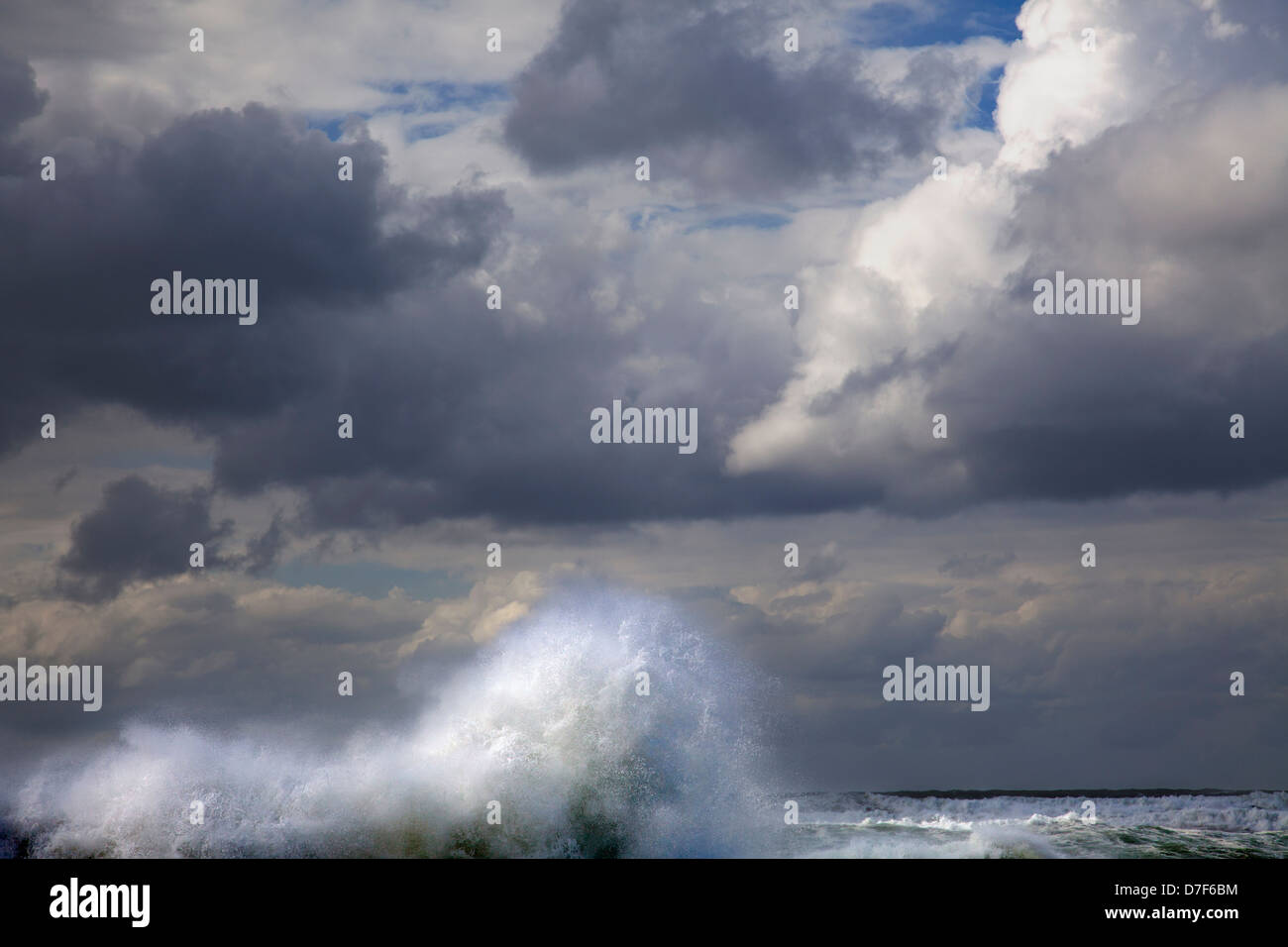 Un onda gigante di innalzarsi al di sopra del mare superficie acqua incoraggiati dal vento impetuoso a toccare pesantemente nuvoloso cielo invernale; in ciò che sembra Foto Stock