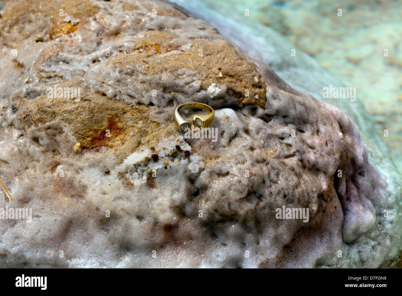 Un oro/Anello oro bianco diamanti intarsiati in appoggio sul sale coperte di sale di roccia. Girato sulla spiaggia infamously salato Mar Morto in Israele. Foto Stock