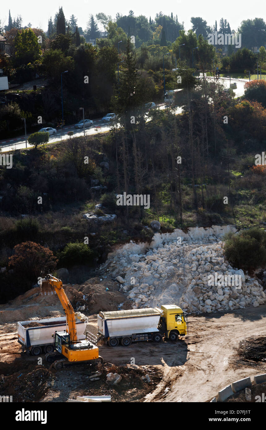 Elevato angolo di visione caricatore anteriore facendo lavori di sterro sul colle rosicchia a lato di collina in rocce carico di sporcizia sul camion pesanti; preparazione Foto Stock