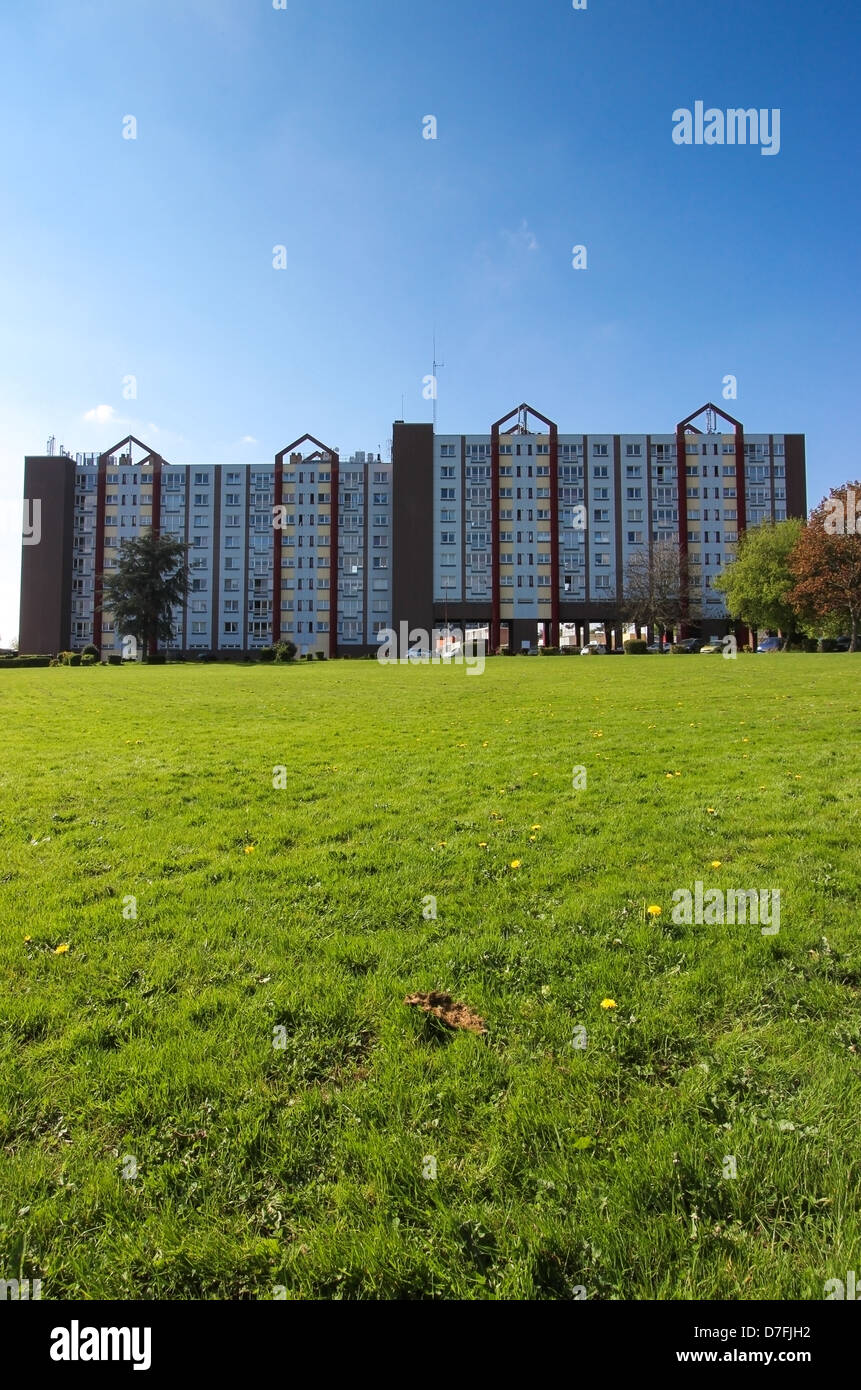 Alloggi sociali edificio con un parco verde nella parte anteriore, cielo blu. Foto Stock