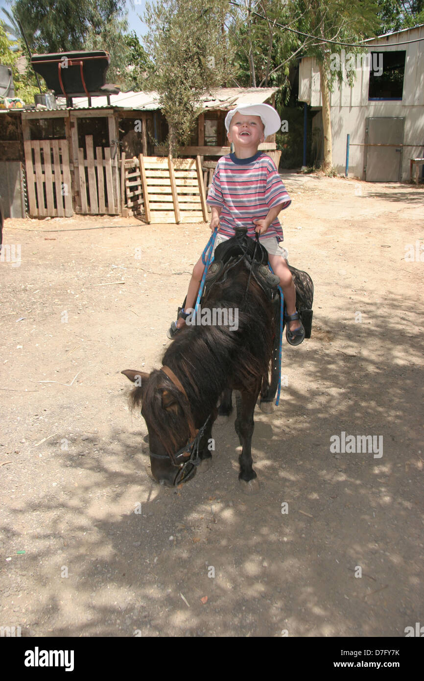 Il bambino si muove su un pony in bitzaron Foto Stock