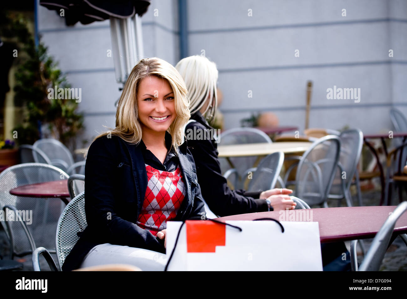 Una giovane donna seduta a un cafè sul marciapiede Foto Stock