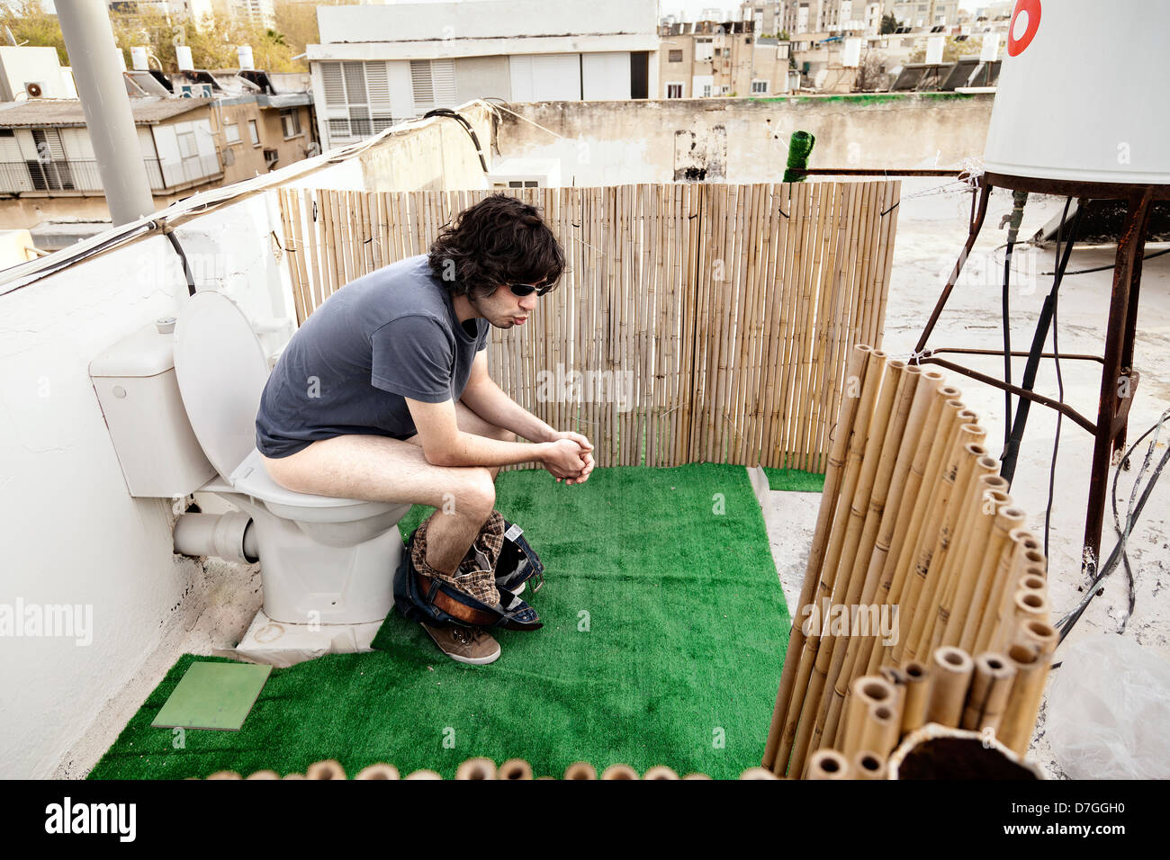 Caucasian uomo adulto nei suoi primi anni trenta sembra essere molto concentrato in utilizzando un tetto esterno wc. Foto Stock