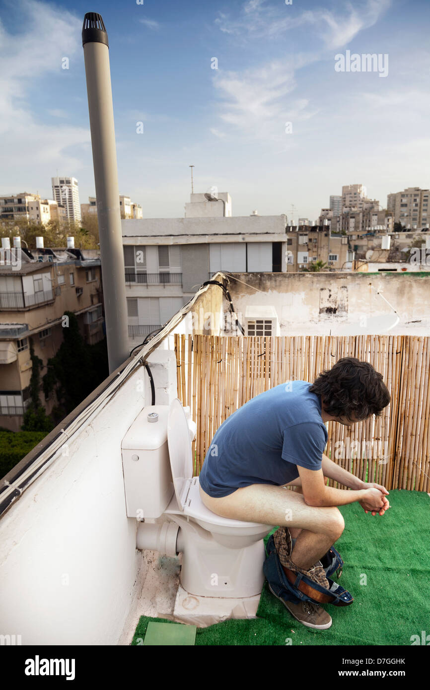 Caucasian uomo adulto nei suoi primi anni trenta sembra essere molto concentrato in utilizzando un tetto esterno wc. Foto Stock