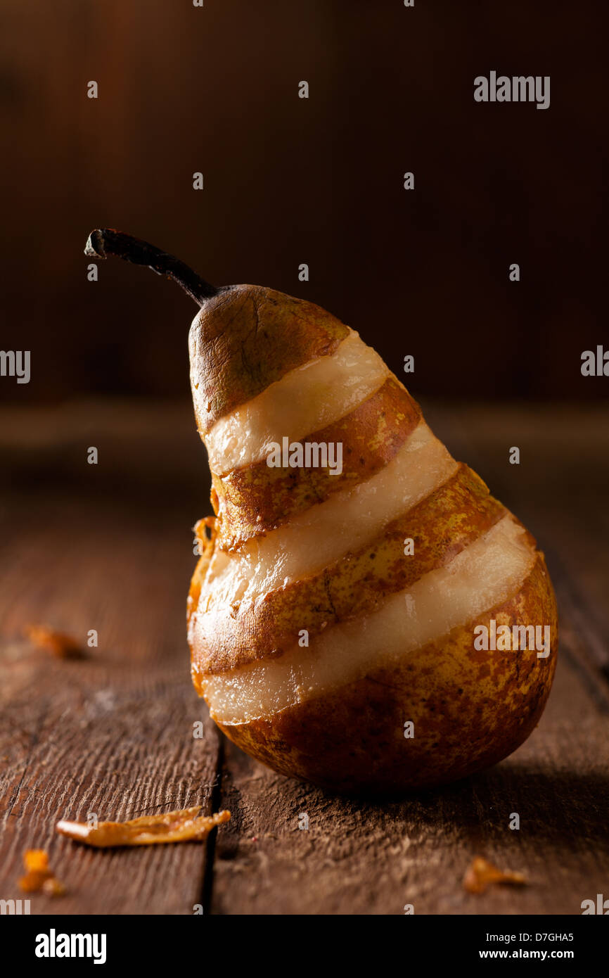 Pera sbucciata con strisce su legno Foto Stock
