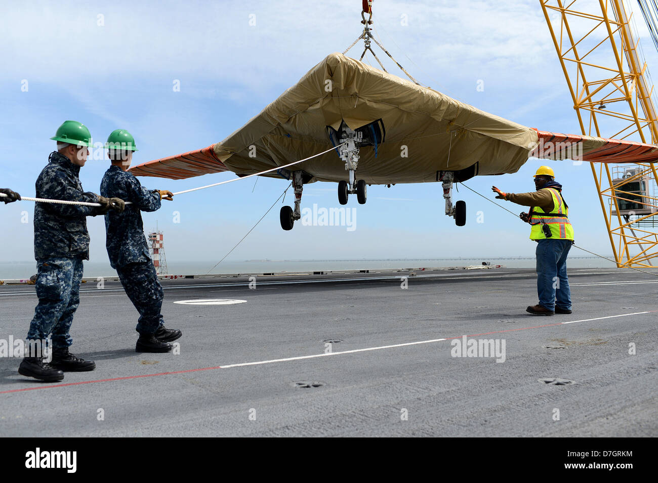 US Navy marinai spostare un X-47B Unmanned Combat Air System aeromobile a bordo della portaerei USS George H.W. Bush Maggio 6, 2013 in Norfolk, VA. La USS George H.W. Bush è programmato per essere la prima portaerei a catapultare il lancio di un velivolo senza equipaggio dal suo ponte di volo. Foto Stock