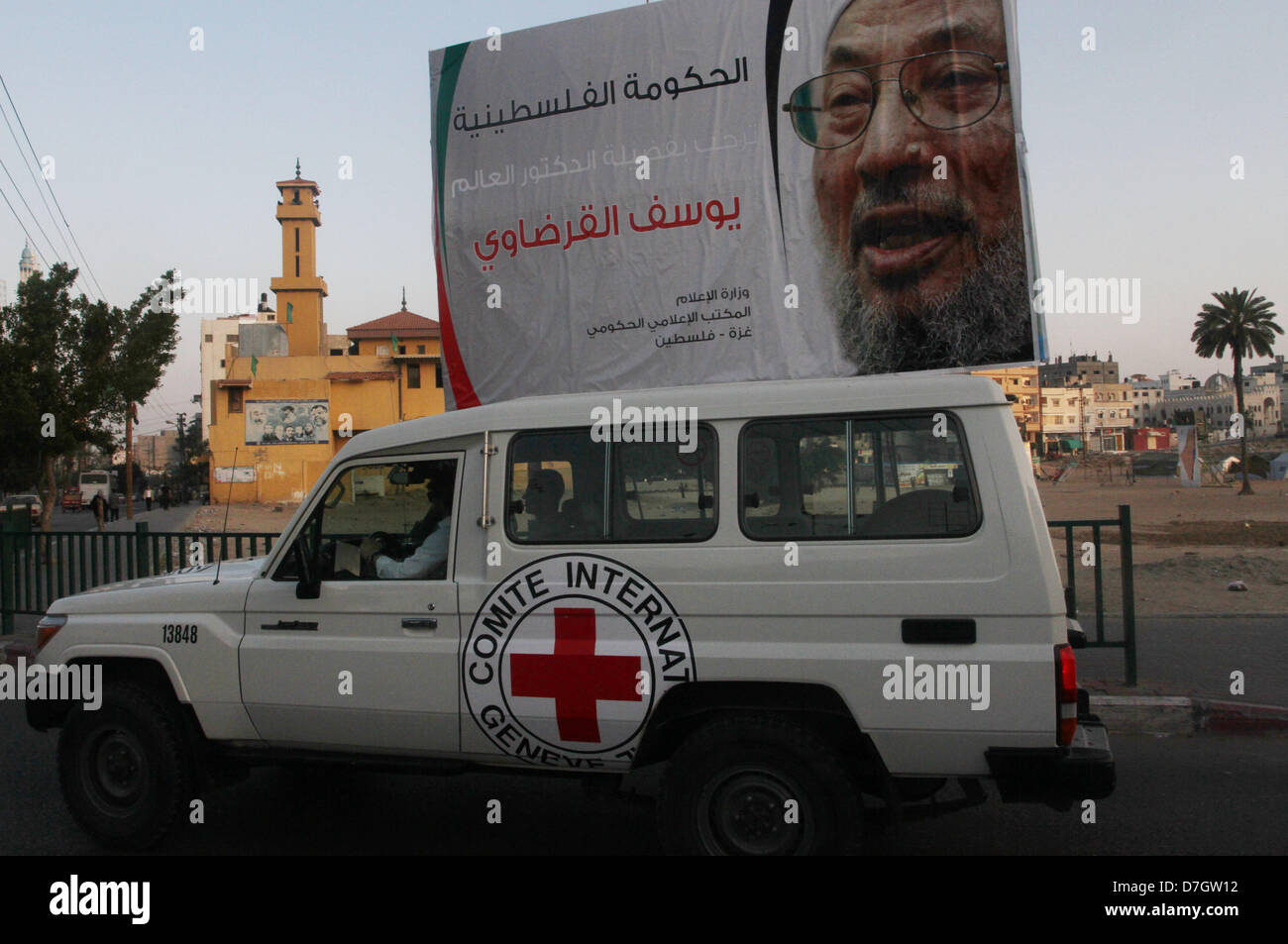 Luglio 31, 2012 - Gaza City, nella Striscia di Gaza, Territori palestinesi - Una vettura è spinto oltre un banner con immagine di eminente studioso Musulmano lo sceicco Yusuf al-Qaradawi, nella Striscia di Gaza City il 7 maggio 2013. Al-Qaradawi, Qatar-basato chierico che è largamente rispettata attraverso il mondo musulmano, e sottolinea il suo sostegno per il gruppo islamico di Hamas, sarà a capo di una delegazione di studiosi di domani nella sua prima visita alla striscia di Gaza (credito Immagine: © Naaman Omar/immagini APA/ZUMAPRESS.com) Foto Stock