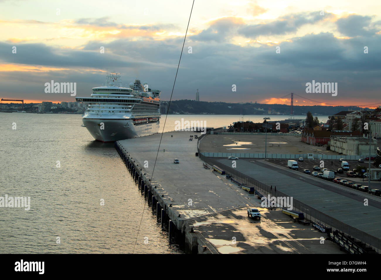 Il terminal delle navi da crociera, con il sole che tramonta oltre il 25 de Abril Bridge, Porto di Lisbona, Portogallo Foto Stock