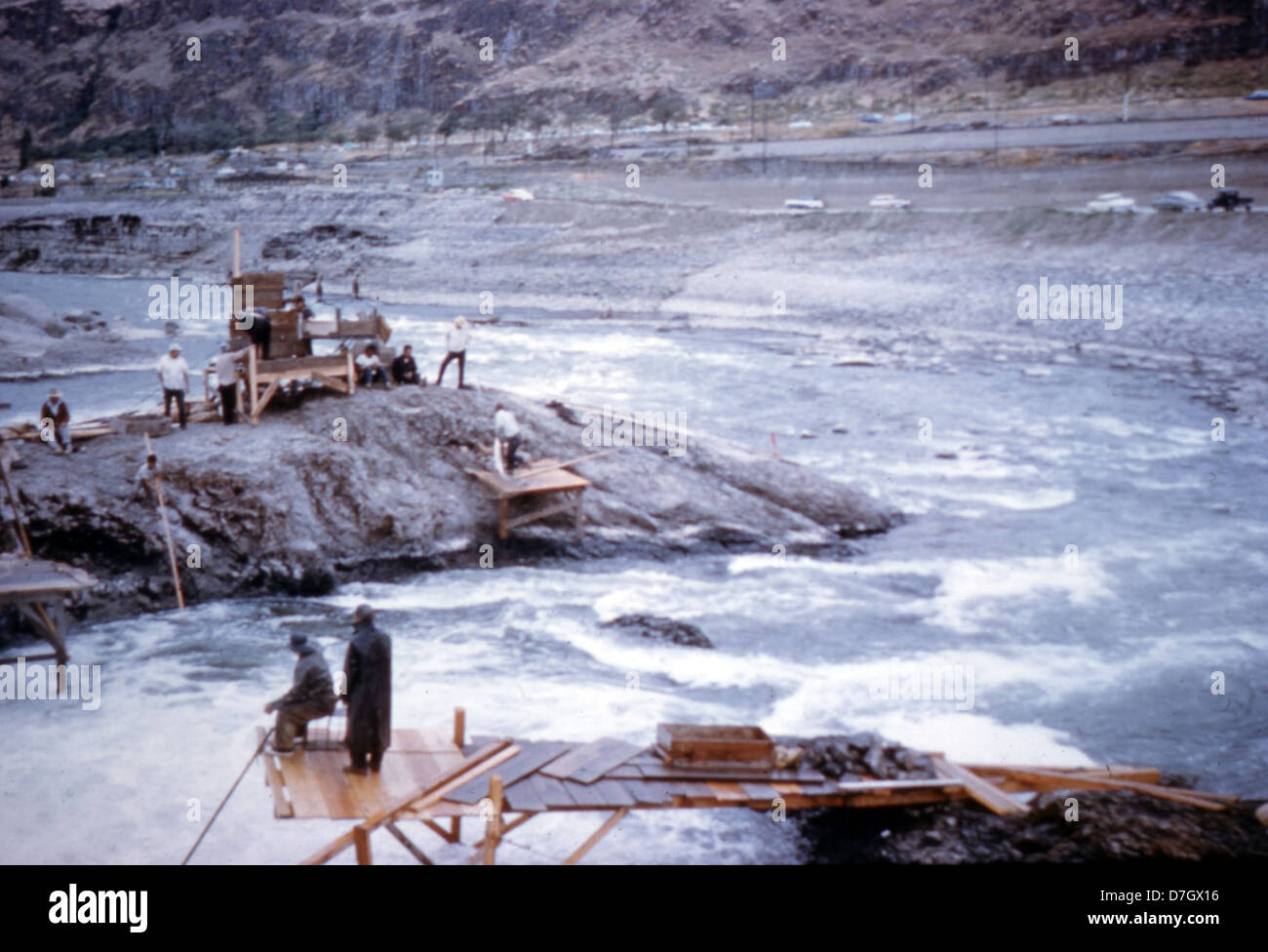 I pescatori vengono mostrati mentre lavorano dalle piattaforme di Celilo Falls, una storica località di pesca sul fiume Columbia. Le cascate erano un sito significativo per le pratiche di pesca dei nativi americani prima della costruzione della diga di Dalles. Questa immagine riflette l'importanza culturale ed economica delle cadute. Foto Stock