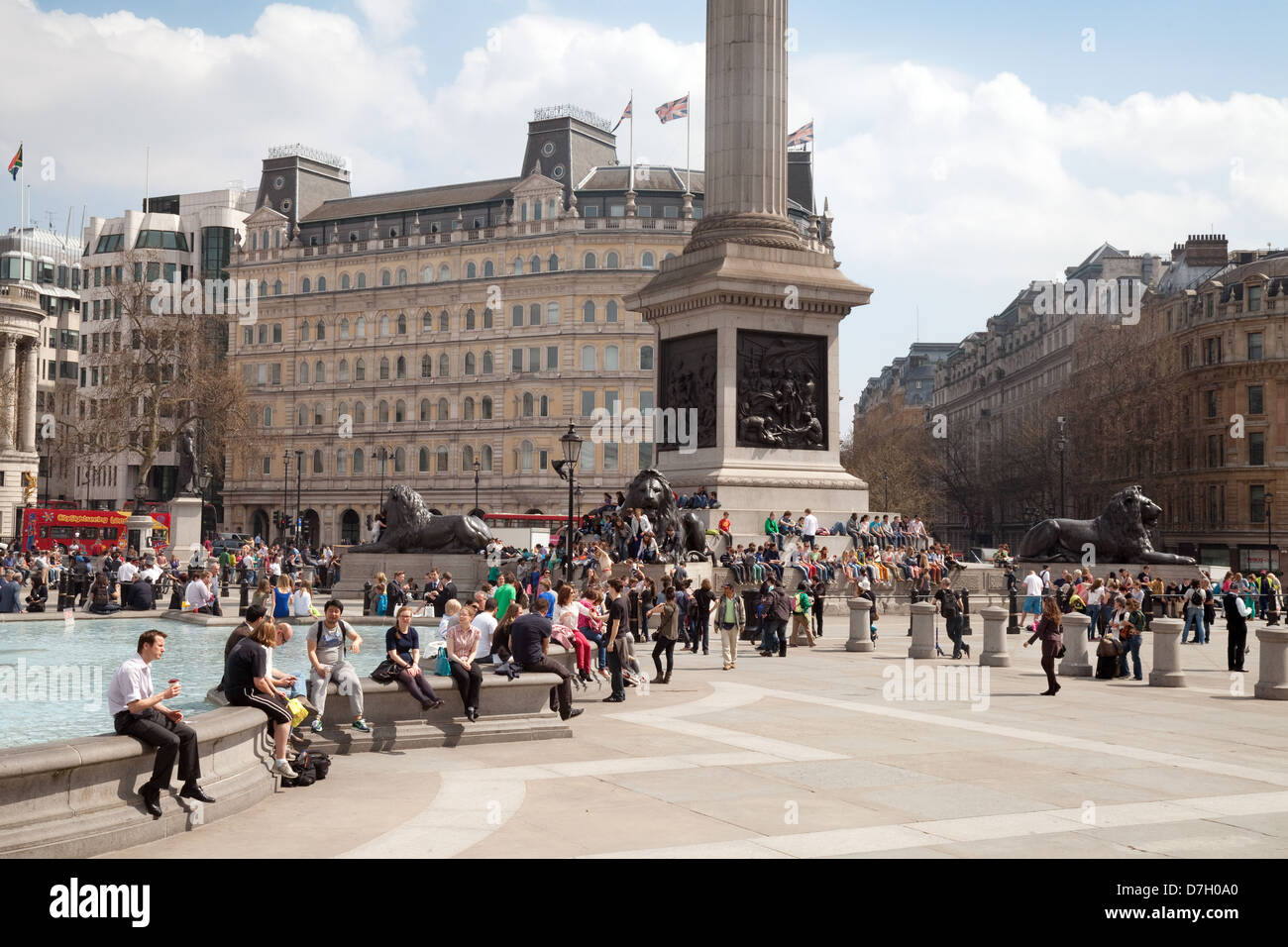 La gente seduta attorno alle fontane in una giornata di sole, Trafalgar Square, Central London WC2, Regno Unito Foto Stock
