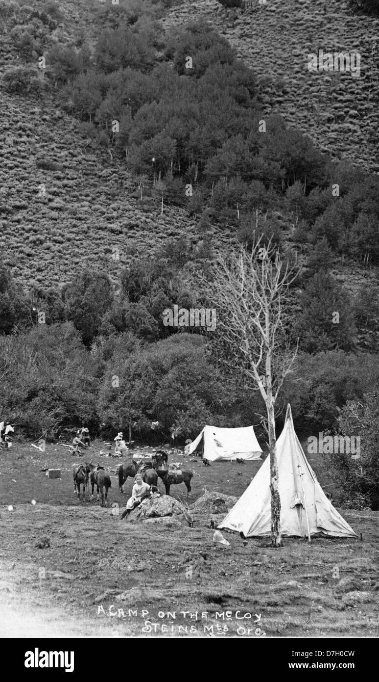 Questa fotografia cattura un accampamento sul McCoy Creek vicino a Steens Mountain in Oregon, mostrando la bellezza panoramica e il paesaggio aspro della regione. L'immagine fa parte della Gerald W. Williams Collection, che mostra lo stile di vita all'aperto e la bellezza naturale dell'Oregon. Foto Stock