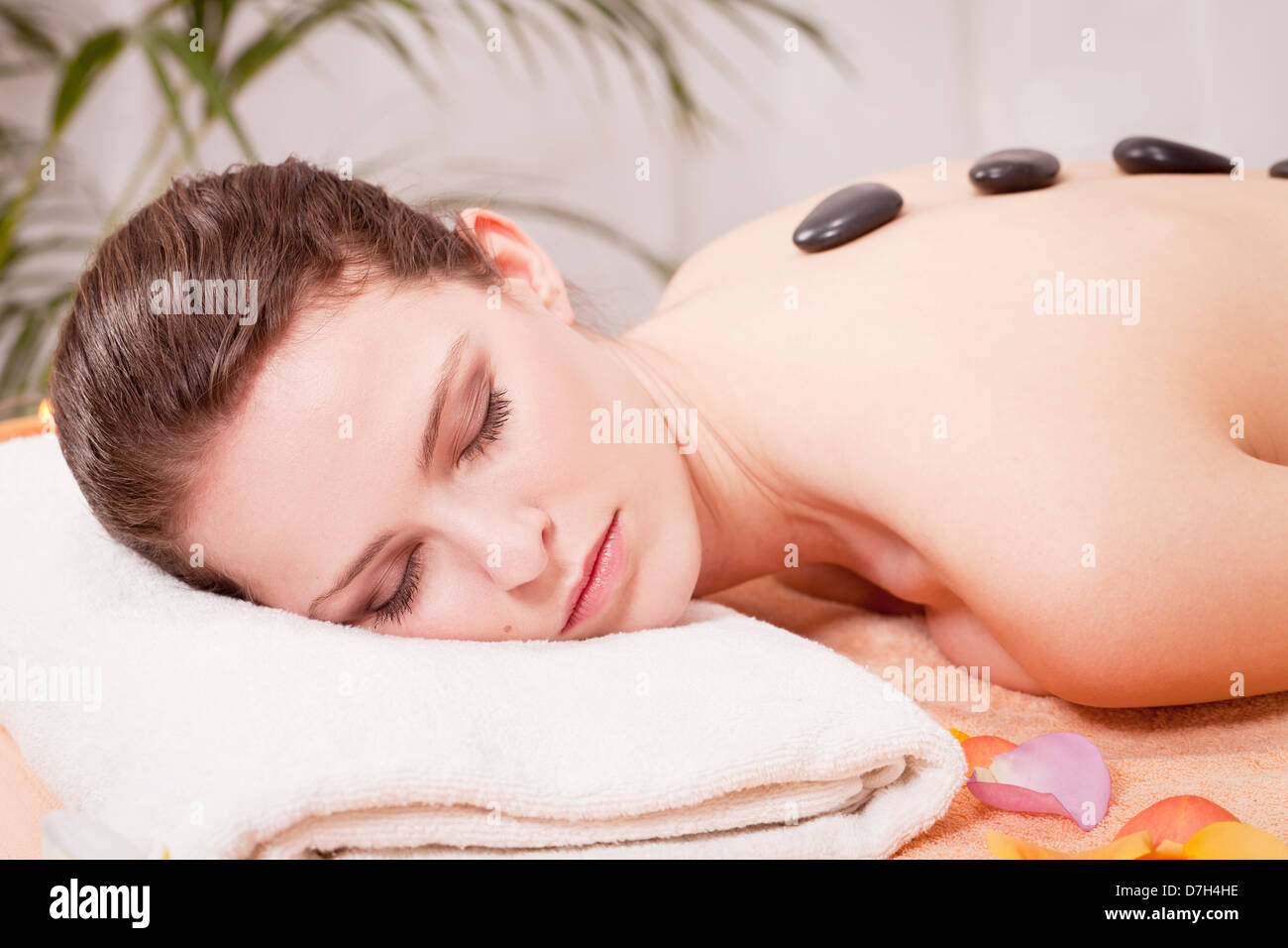 Giovane donna attraente ottenere un massaggio con pietre calde da professionisti in wellness spa salone Foto Stock