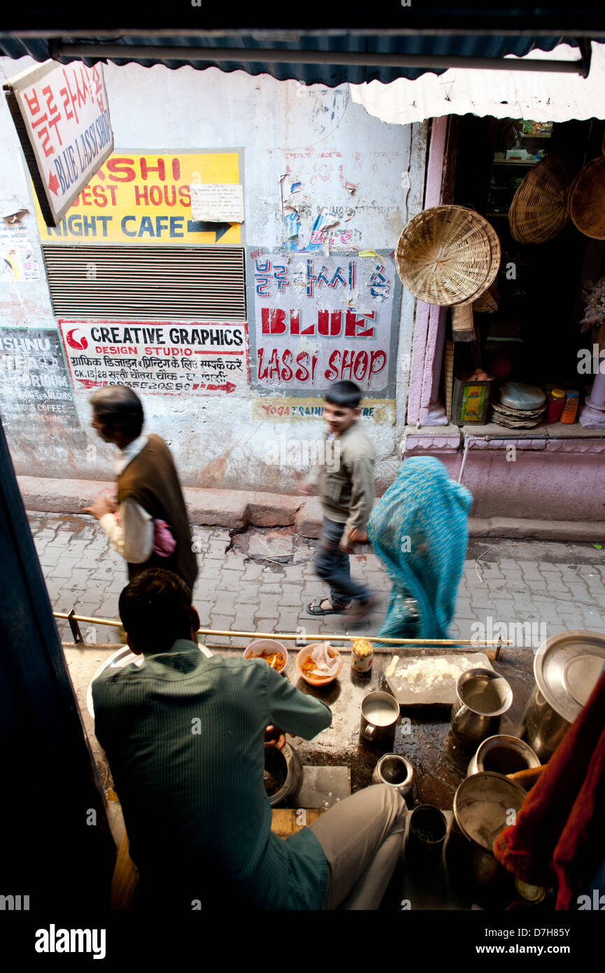 La gente a piedi passato il famoso Blue Lassi Shop nei vicoli di Varanasi e non lontano dal fiume Gange. India Foto Stock