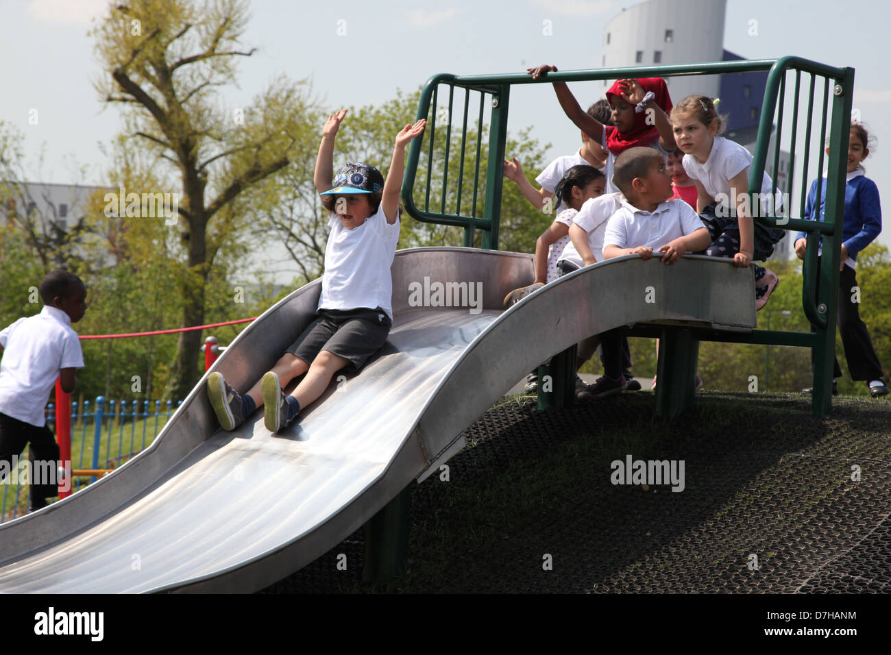 Bambini che giocano su una diapositiva in un parco giochi a Londra Foto Stock