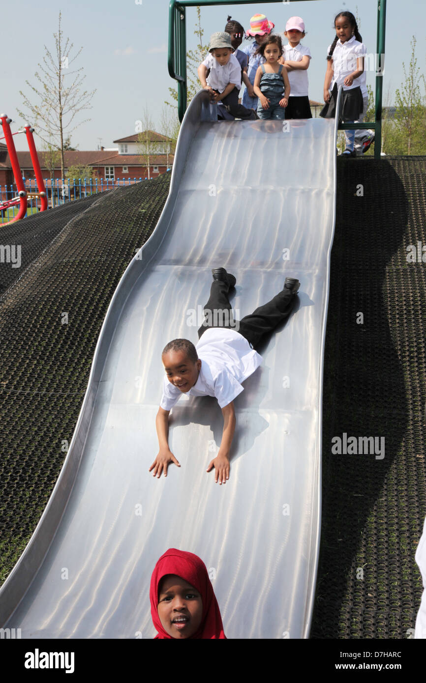 Bambini che giocano su una diapositiva in un parco giochi a Londra Foto Stock