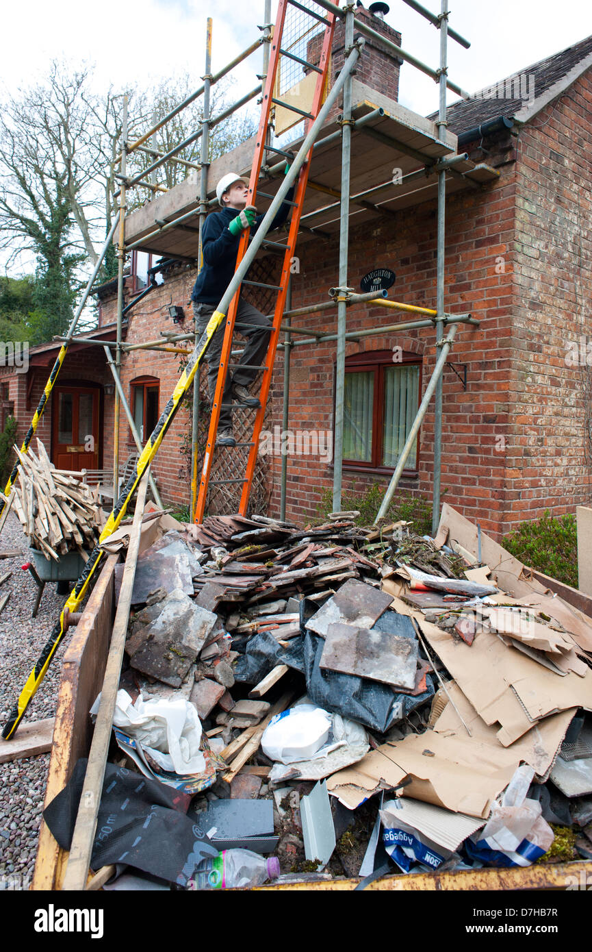 Un builder salendo una scala durante i lavori di costruzione di una casa Foto Stock