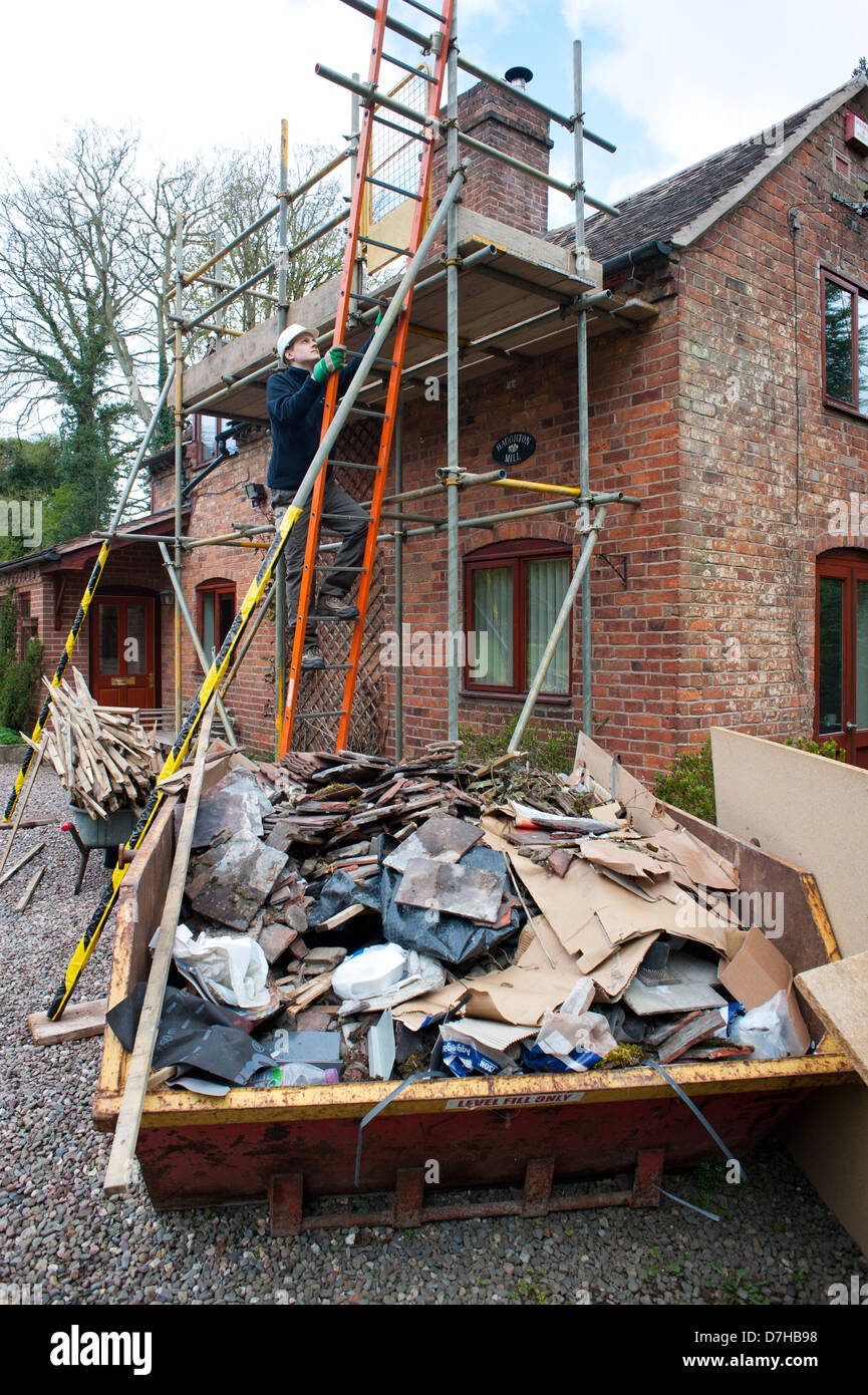 Un builder salendo una scala durante i lavori di costruzione di una casa Foto Stock