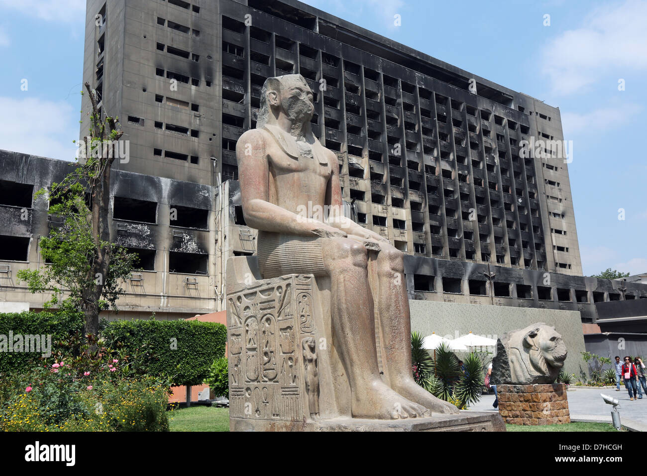 L'Egitto, al Cairo. Antiche Figure scolpite al cortile del museo egizio, a sfondo bruciato NDP-edificio di partito Foto Stock
