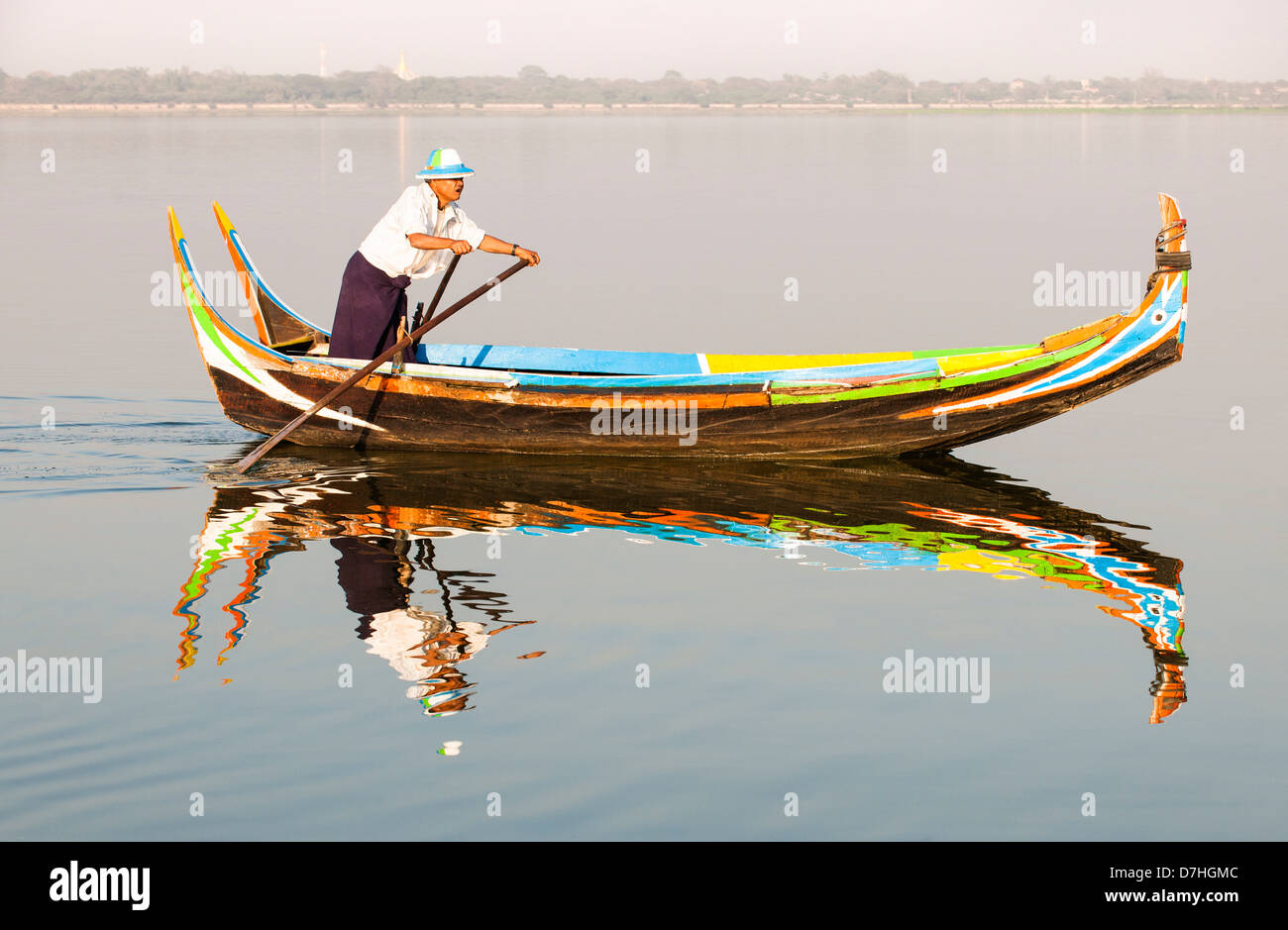 Un barcaiolo prendendo la sua barca di legno tradizionale attraverso il lago Taungthaman, Amarapura, Mandalay Birmania (Myanmar) Foto Stock