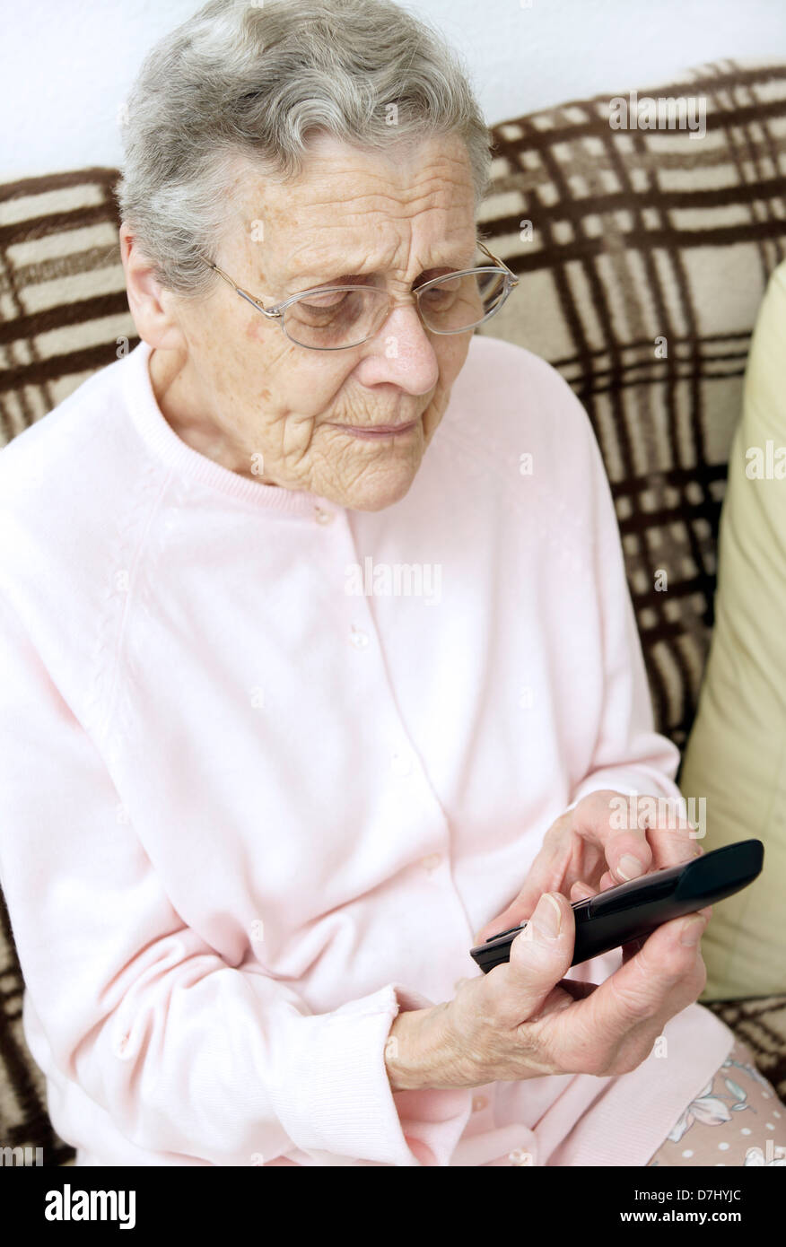 Donna anziana utilizzando un settore specializzato in grande pulsante telefono chiamando il 111 in situazioni di non emergenza consulenza medica helpline a causa di malessere Foto Stock