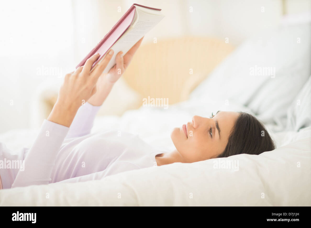Donna giaceva a letto e un libro di lettura Foto Stock