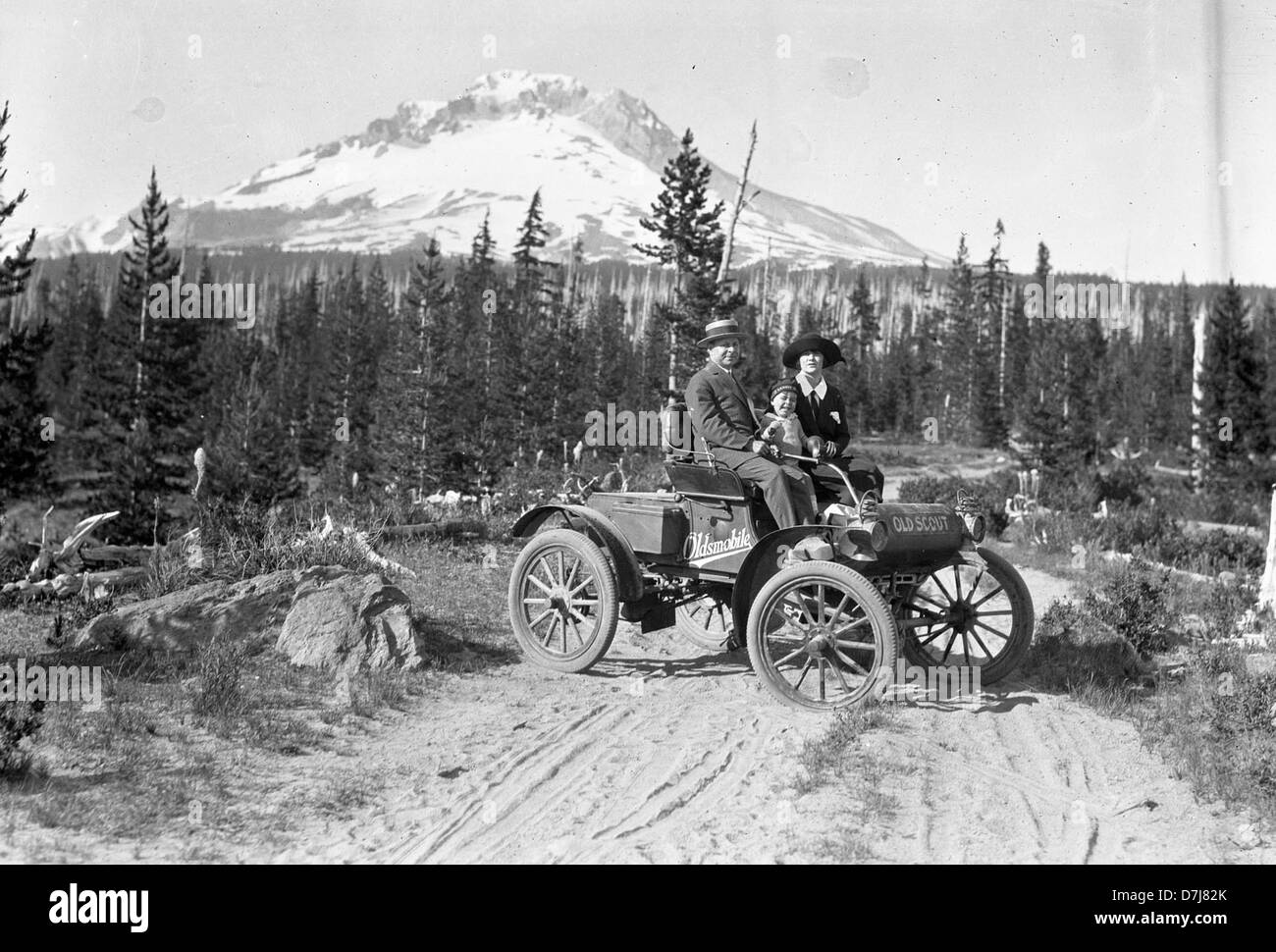 Questa fotografia cattura una famiglia che viaggia insieme in un classico Oldsmobile, conosciuto come l'Old Scout. L'immagine evoca un senso di nostalgia, ritraendo un tempo in cui i viaggi in famiglia erano una parte significativa della cultura americana e l'Oldsmobile era un veicolo popolare per queste avventure. Foto Stock