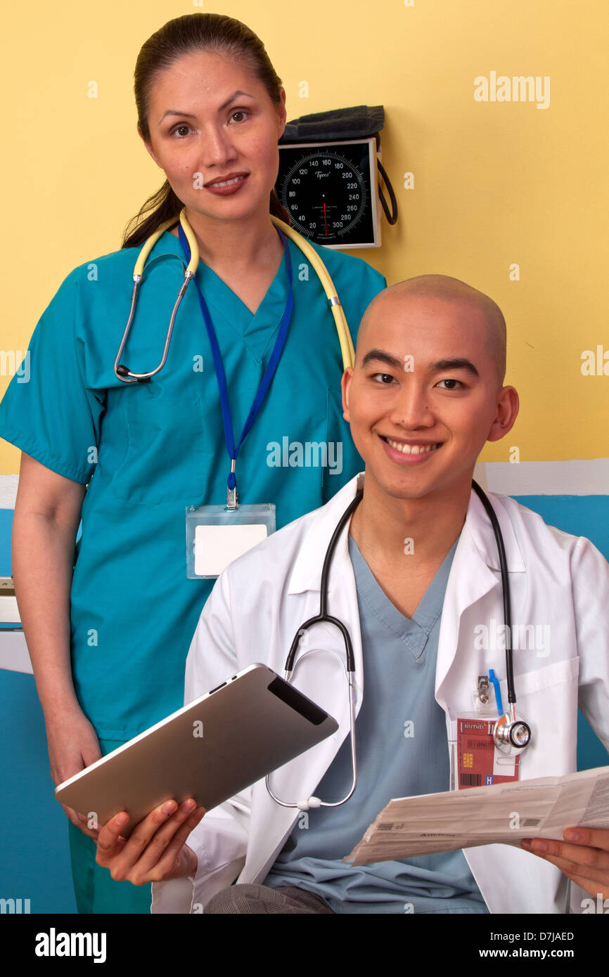 Ritratto di medico e infermiere in sala esame, sorridente. Medico tenendo compressa. Foto Stock