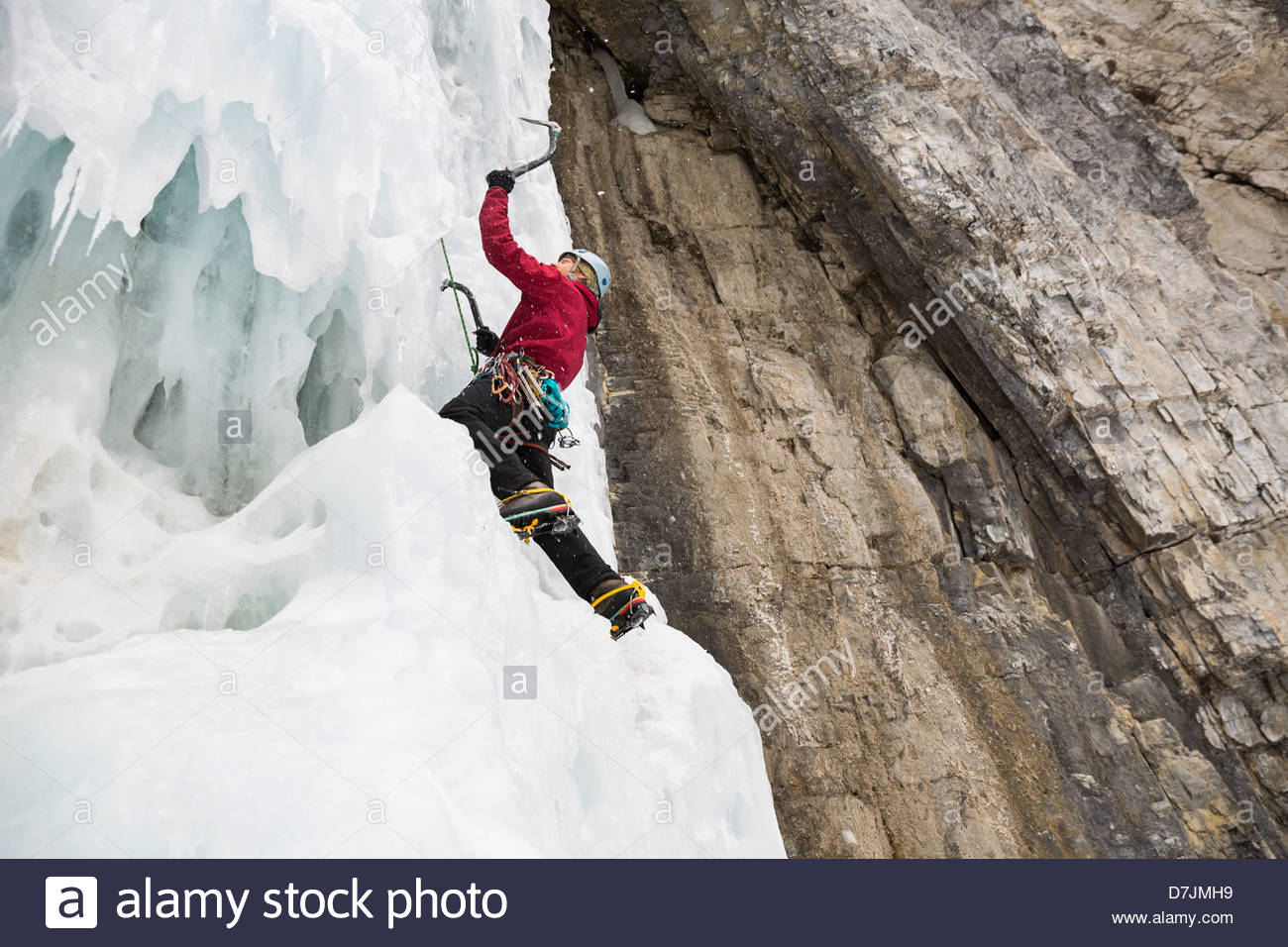 Basso angolo di visione dell'uomo arrampicata parete di ghiaccio in montagna Foto Stock