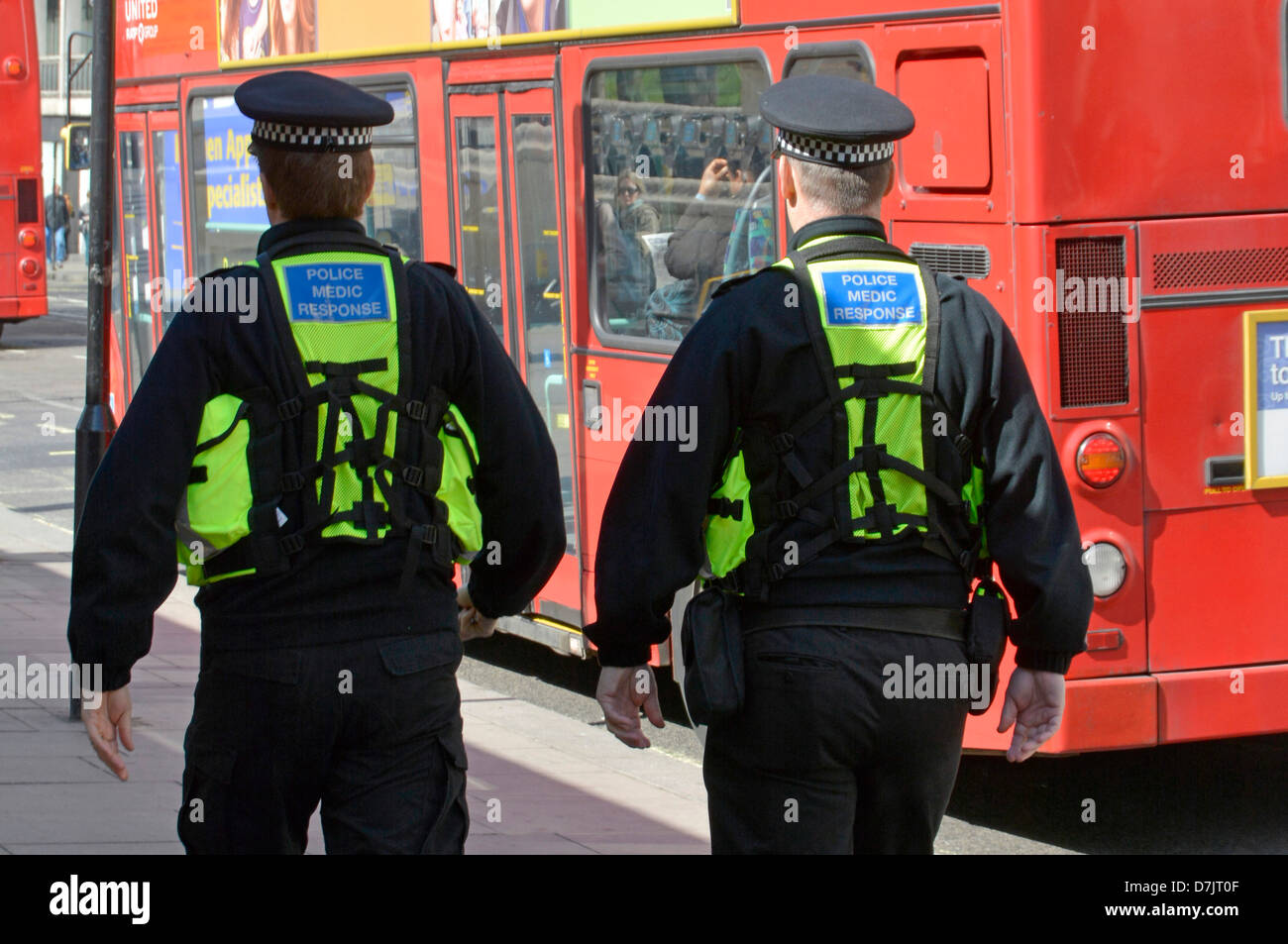 Primo piano vista posteriore di due agenti medici di polizia di risposta In zaini uniformi sui poliziotti metropolitani in pattuglia a piedi West End Londra Inghilterra Regno Unito Foto Stock