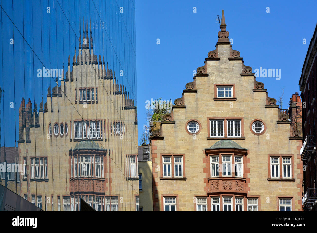 Vecchio edificio e la sua riflessione sul moderno rivestimento in vetro per ufficio nuovo blocco Foto Stock