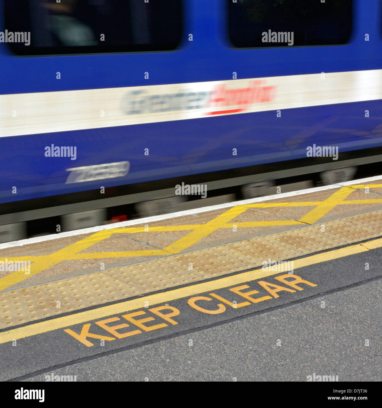 Piattaforma della stazione ferroviaria tenere chiari segnali di sicurezza pavimentazione antiscivolo e linea gialla tratteggio con veloce treno Greater Anglia che passa da Inghilterra UK Foto Stock